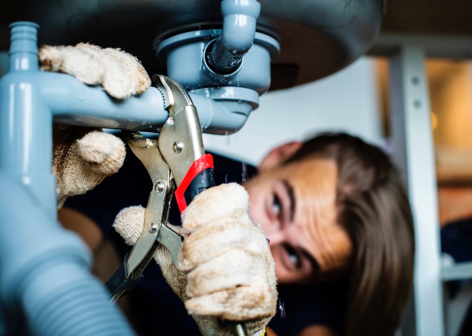 Expert drain cleaner repairing a kitchen sink and clearing a clogged kitchen drain in Dallas, TX.