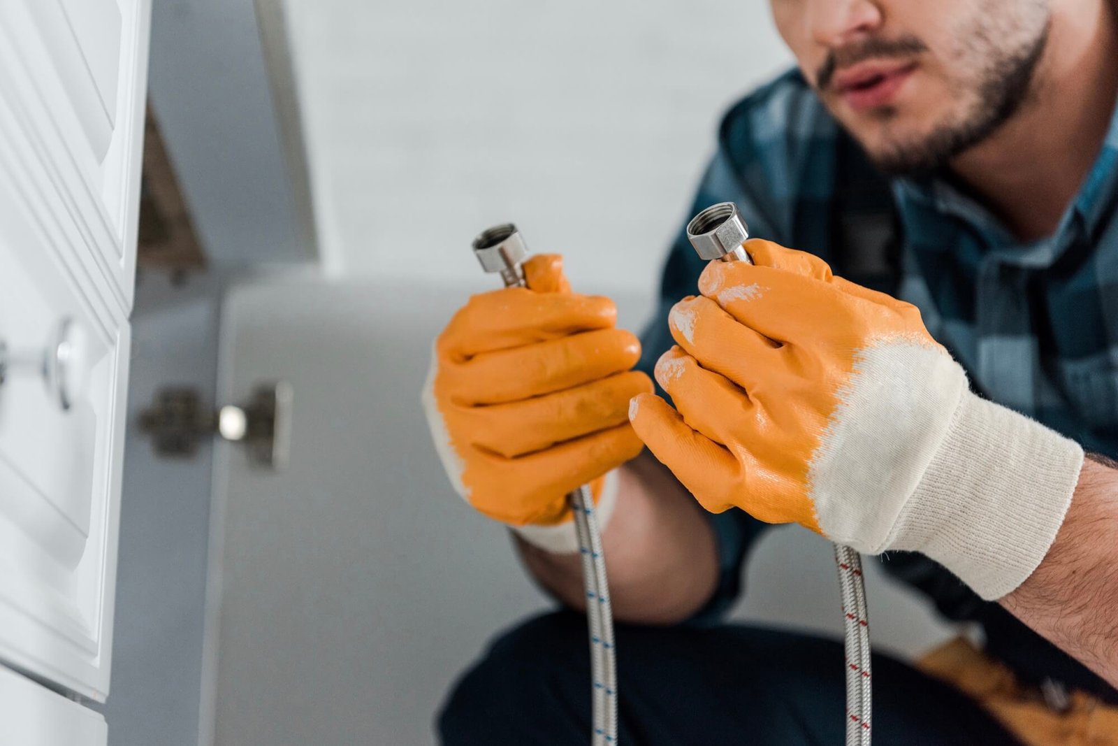 Professional drain cleaner inspecting a flexible metal drain hose during a drain cleaning service in Dallas, TX.